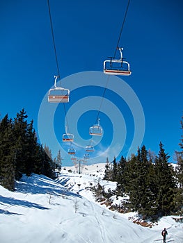 Chairlift with orange seats on blue sky