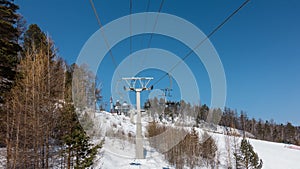 Chairlift over a snow-covered mountainside against a blue sky.