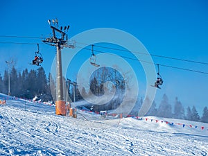 Chairlift, skiers and snow cannons in action