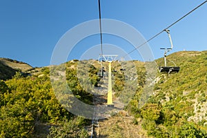 Chairlift to top of hill of mountain with blue sky in background. Sightseeing concept. Excursions at vacation. Sunny day