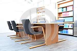 Chairs around a table in a conference room with bookshelves in the background