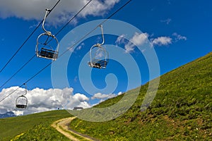 Chairs of a chairlift dangle over a hiking trail photo