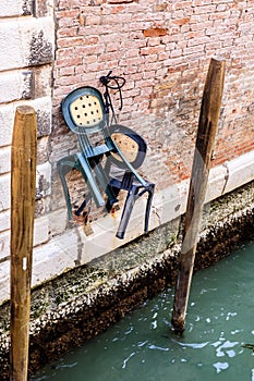 Chairs hanging on the brick wall over Venice canal. Italy, Europe