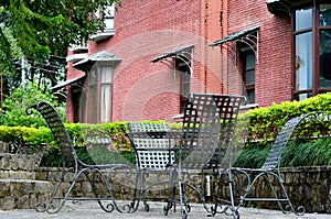 Chairs in a hedged area with brick wall