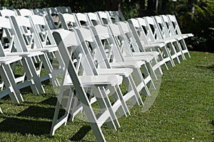 Chairs placed on a green lawn set up for an outdoor wedding ceremony