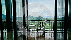 Chairs for relaxation and watching the mountains., Overlooking the window of a balcony with transparent curtains and nice view