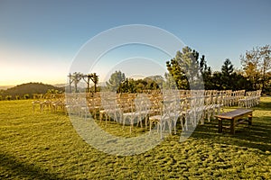 Chairs set up on a lawn for a wedding cerimony with no people yet from the back