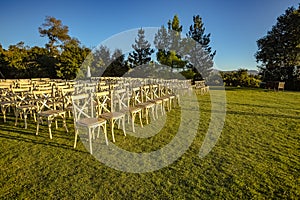 Chairs set up on a lawn for a wedding cerimony with no people yet from the front