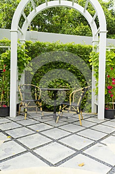 Chairs and table in a beautiful garden canopy in home landscaped garden in summer.