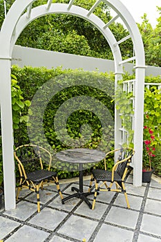 Chairs and table in a beautiful garden canopy in home landscaped garden in summer.