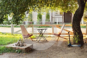 Chairs and table table in summer garden with outdoor stone fireplace. Wooden outdoor furniture set for Picnic or leisure time in n