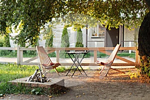 Chairs and table table in summer garden with outdoor stone fireplace. Wooden outdoor furniture set for Picnic or leisure time in n