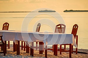 Chairs and table with tablecloth on a tropical beach at sunset