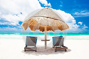 Chairs and umbrella on white sand beach in Tulum