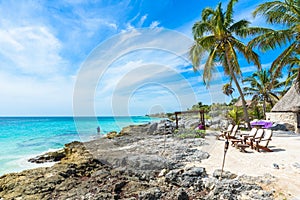 Chairs under the palm trees on paradise beach at tropical Resort. Riviera Maya - Caribbean coast at Tulum in Quintana Roo, Mexico