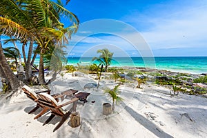 Chairs under the palm trees on paradise beach at tropical Resort. Riviera Maya - Caribbean coast at Tulum in Quintana Roo, Mexico