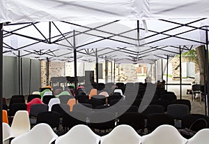 Chairs under a white canopy area for event guests