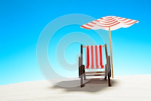 A chaise longue under an umbrella on the sandy beach, sky with copy space