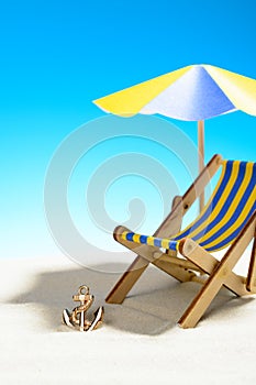 A chaise longue under an umbrella on the sandy beach, sky with copy space