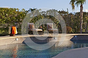 Chaise lounge chairs at poolside of manor house