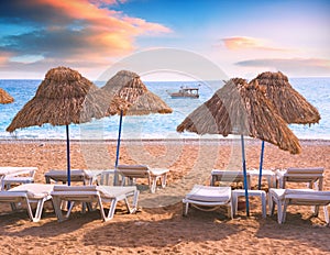 Chaise lounge under the straw umbrellas on a beach