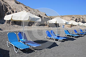 Chaise lounges on black beach of Santorini island, Greece