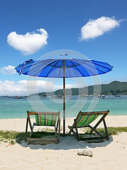 A chaise lounges and dark blue beach umbrella