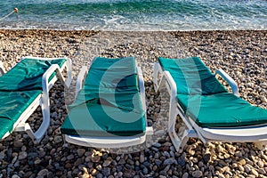 Chaise lounges on pebble beach. Concept of rest, relaxation, holidays, resort