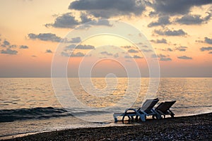 Chaise lounges by the sea at sunset. Romantic mood