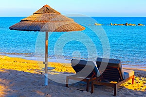 Chaise lounges and straw umbrella of beach