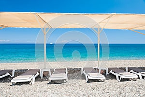 Chaise lounges under the tent on the pebble beach