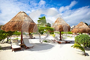 Chaise lounges under an umbrella on sandy beach