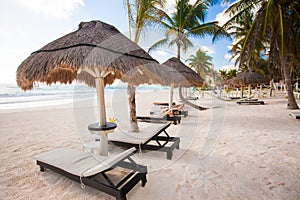 Chaise lounges under an umbrella on white sandy