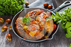 Chakhokhbili, chicken stew, cooked with tomatoes, bell peppers, spices and herbs. Dark wooden background photo