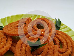 Chakli in a Green Plate isolated on White Background. Indian Snack Chakli or chakali made from deep frying portions of a lentil