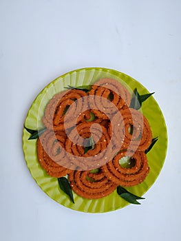 Chakli in a Green Plate isolated on White Background. Indian Snack Chakli or chakali made from deep frying portions of a lentil