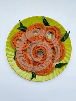 Chakli in a Green Plate isolated on White Background. Indian Snack Chakli or chakali made from deep frying portions of a lentil