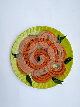 Chakli in a Green Plate isolated on White Background. Indian Snack Chakli or chakali made from deep frying portions of a lentil