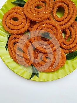 Chakli in a Green Plate isolated on White Background. Indian Snack Chakli or chakali made from deep frying portions of a lentil