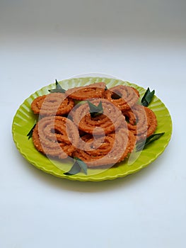 Chakli in a Green Plate  on White Background. Indian Snack Chakli or chakali made from deep frying portions of a lentil