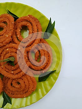 Chakli in a Green Plate  on White Background. Indian Snack Chakli or chakali made from deep frying portions of a lentil