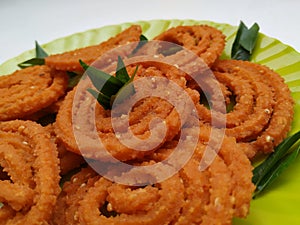 Chakli in a Green Plate  on White Background. Indian Snack Chakli or chakali made from deep frying portions of a lentil