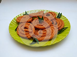 Chakli in a Green Plate  on White Background. Indian Snack Chakli or chakali made from deep frying portions of a lentil