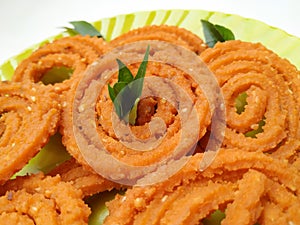 Chakli in a Green Plate  on White Background. Indian Snack Chakli or chakali made from deep frying portions of a lentil