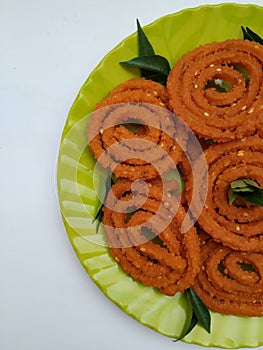 Chakli in a Green Plate  on White Background. Indian Snack Chakli or chakali made from deep frying portions of a lentil