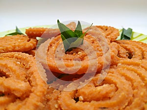 Chakli in a Green Plate  on White Background. Indian Snack Chakli or chakali made from deep frying portions of a lentil