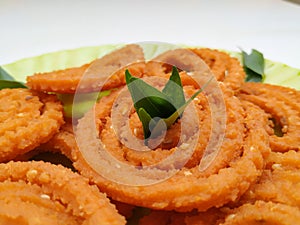 Chakli in a Green Plate  on White Background. Indian Snack Chakli or chakali made from deep frying portions of a lentil