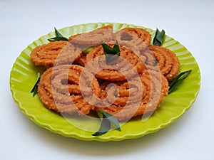 Chakli in a Green Plate  on White Background. Indian Snack Chakli or chakali made from deep frying portions of a lentil