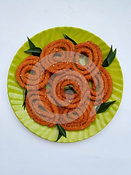 Chakli in a Green Plate  on White Background. Indian Snack Chakli or chakali made from deep frying portions of a lentil