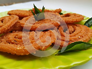 Chakli in a Green Plate  on White Background. Indian Snack Chakli or chakali made from deep frying portions of a lentil